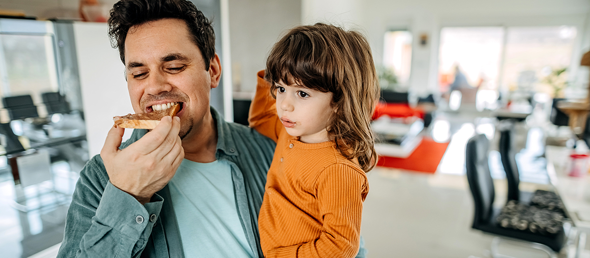 Father and son in the kitchen. Father has breakfast