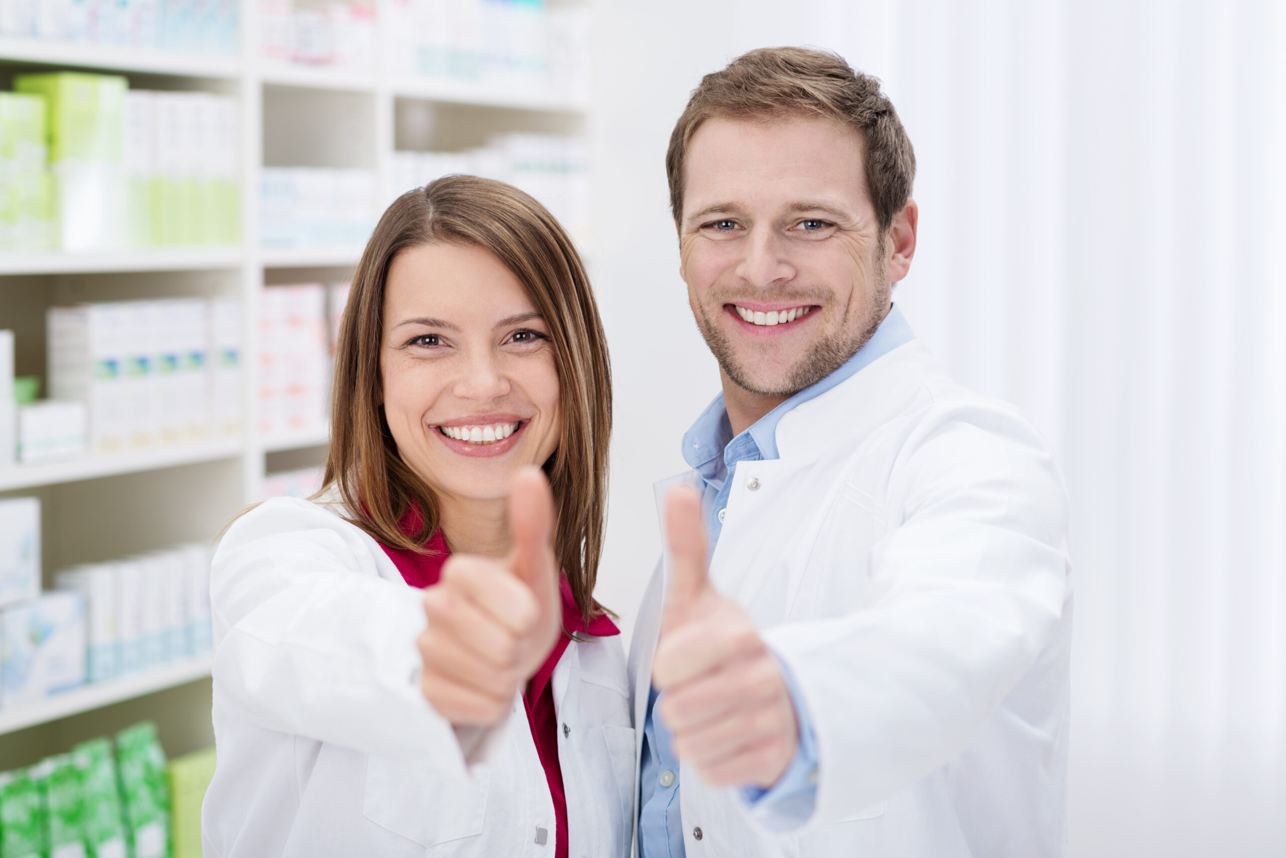 Two,Motivated,Young,Pharmacists,Giving,A,Thumbs,Up,Of,Approval